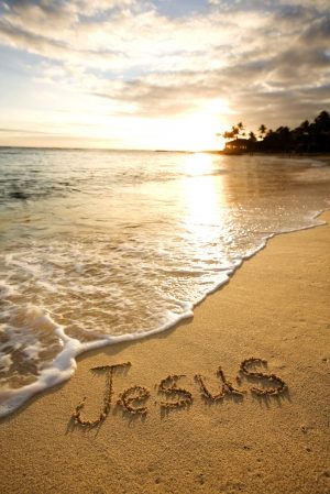 beach scene with "Jesus" written in the sand